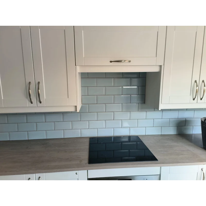 Kitchen with blue-grey subway tile splashback and white cabinets
