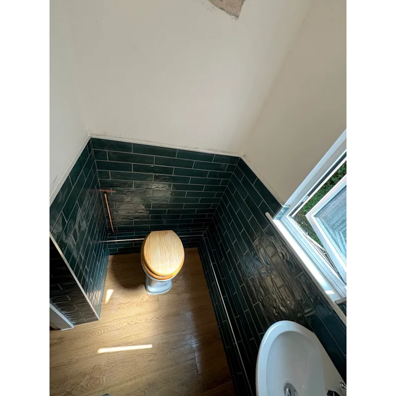 Bathroom WC with dark green subway tiles