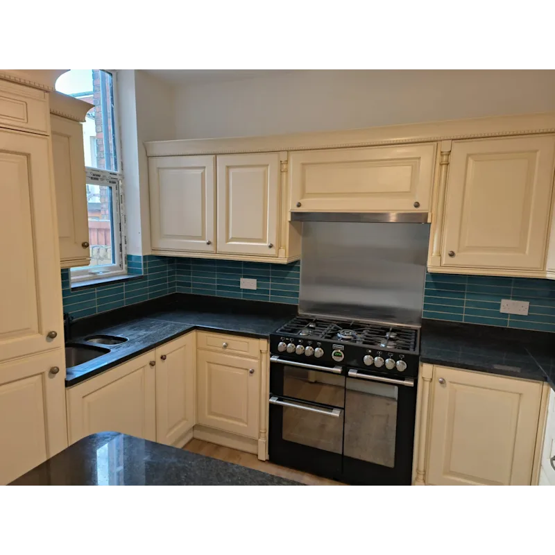Kitchen with teal-blue tiles, cream cabinets, and range cooker