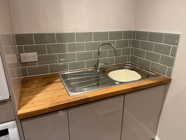 Small kitchen splashback with grey subway tiles and wooden worktop